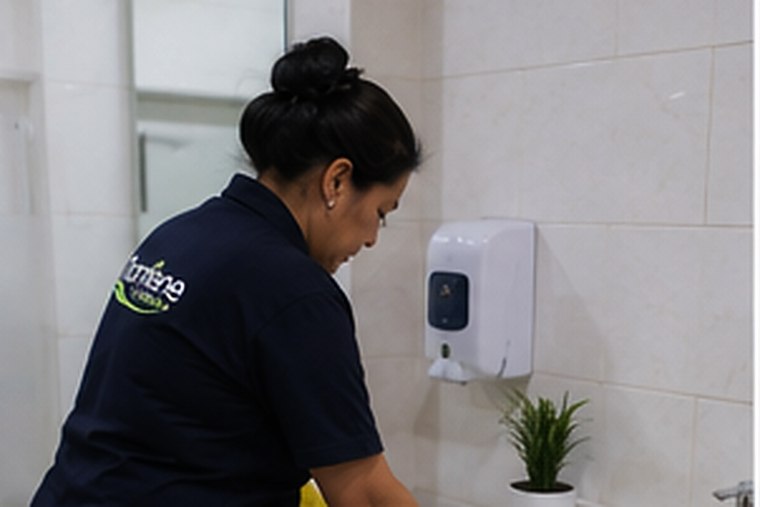 Auxiliar de Mantiene sanitizando un baño corporativo