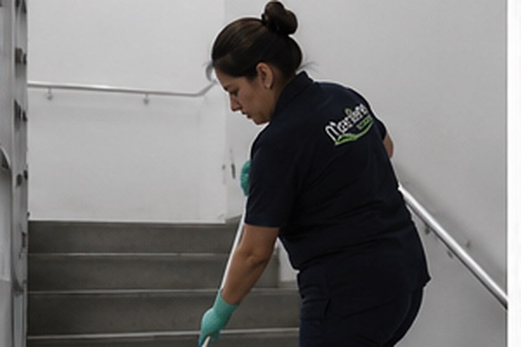 Auxiliar de Mantiene limpiando la escalera de un edificio