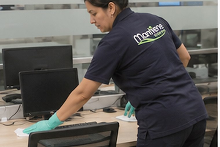 Auxiliar de Mantiene desinfectando puestos de trabajo en una oficina