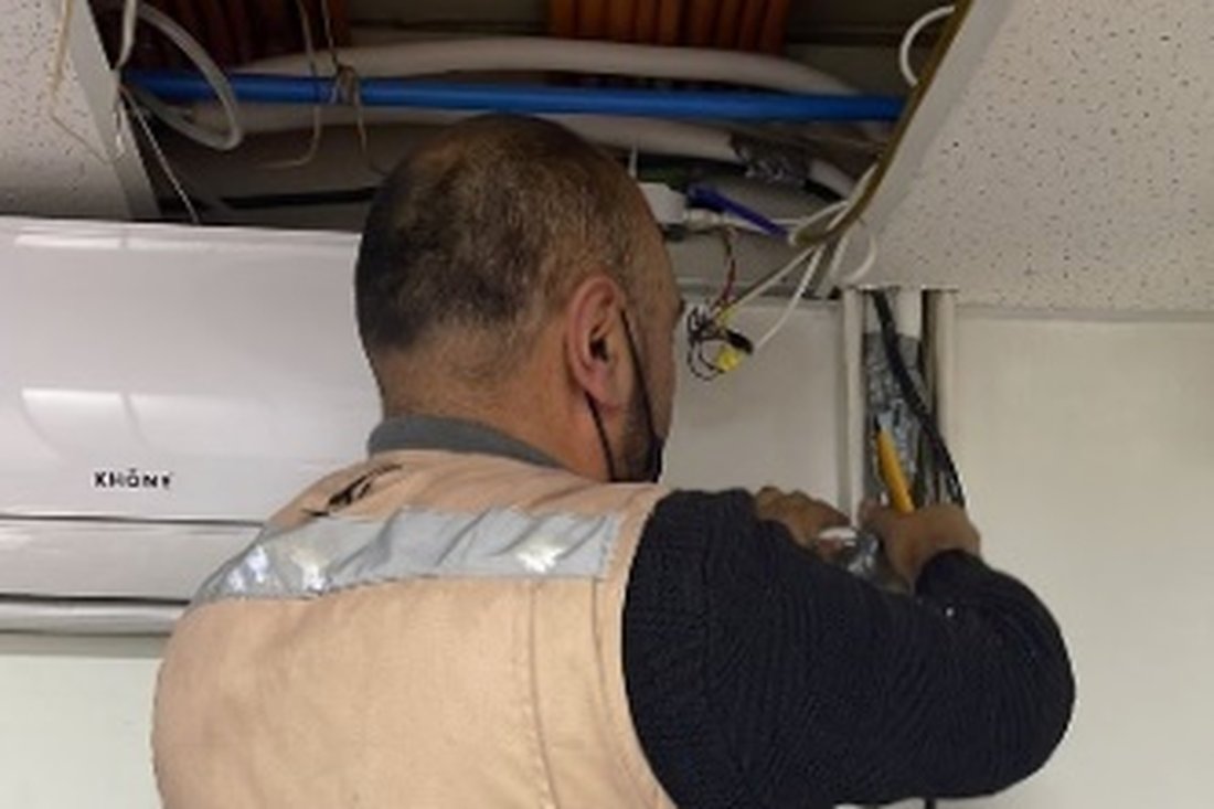 Técnico de Mantiene revisando un equipo de clima sobre el cielo falso