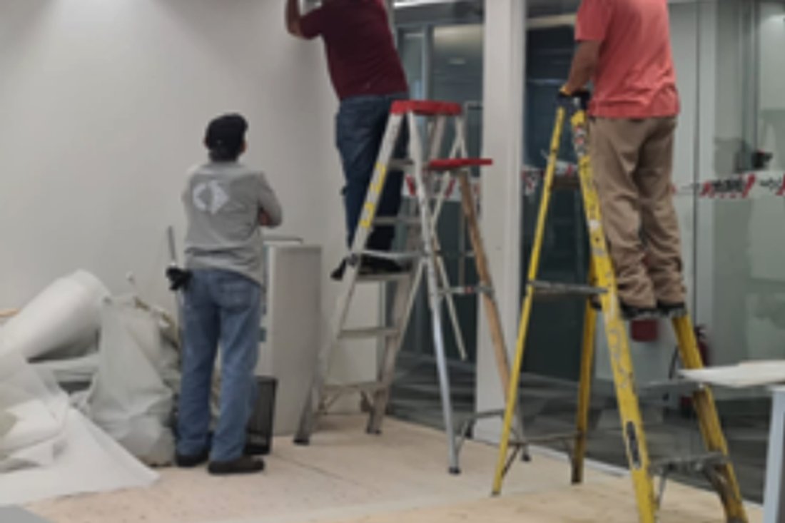 Equipo de Mantiene montando iluminación lineal en el cielo de una oficina
